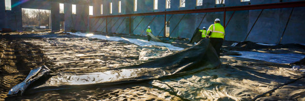 Construction workers laying down ground thaw blankets